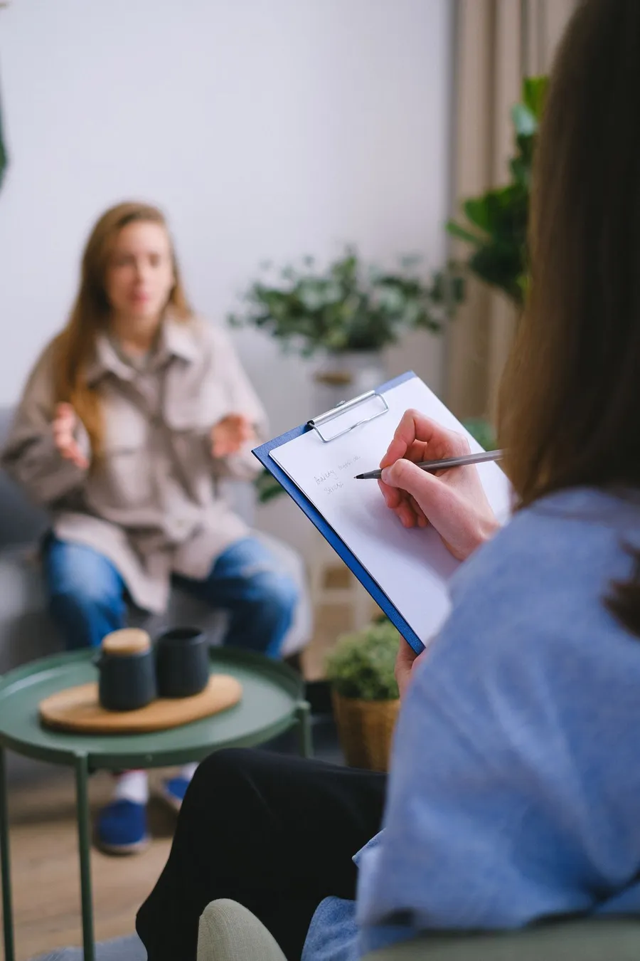 A therapist taking notes during a calm session in a plant-filled room